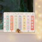 Tableau magnétique Ma jolie semaine édition Noël de l’Atelier Gigogne posé sur un rebord de fenêtre illuminé, pour aider les enfants à se repérer dans le temps avec douceur et magie.