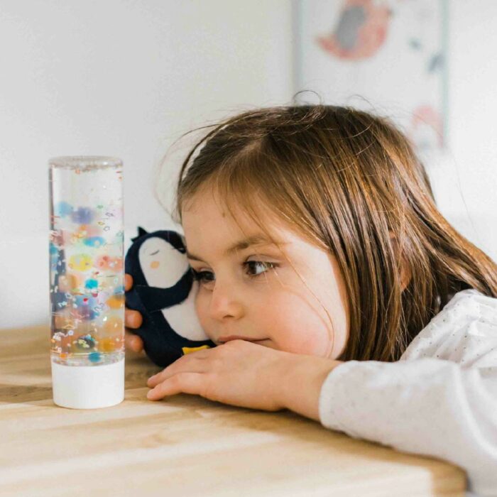 Enfant observant la bouteille sensorielle du kit de retour au calme de l’Atelier Gigogne, un outil pour apaiser les émotions et retrouver le calme.