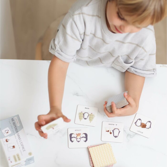 Enfant manipulant des cartes éducatives pour apprendre le repérage spatial en jouant.