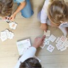 Enfants apprenant à compter avec un jeu de cartes éducatif, accompagnés d’un adulte.